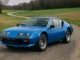 Alpine A310 bleue des années 1970, vue de trois-quarts avant sur route de campagne
